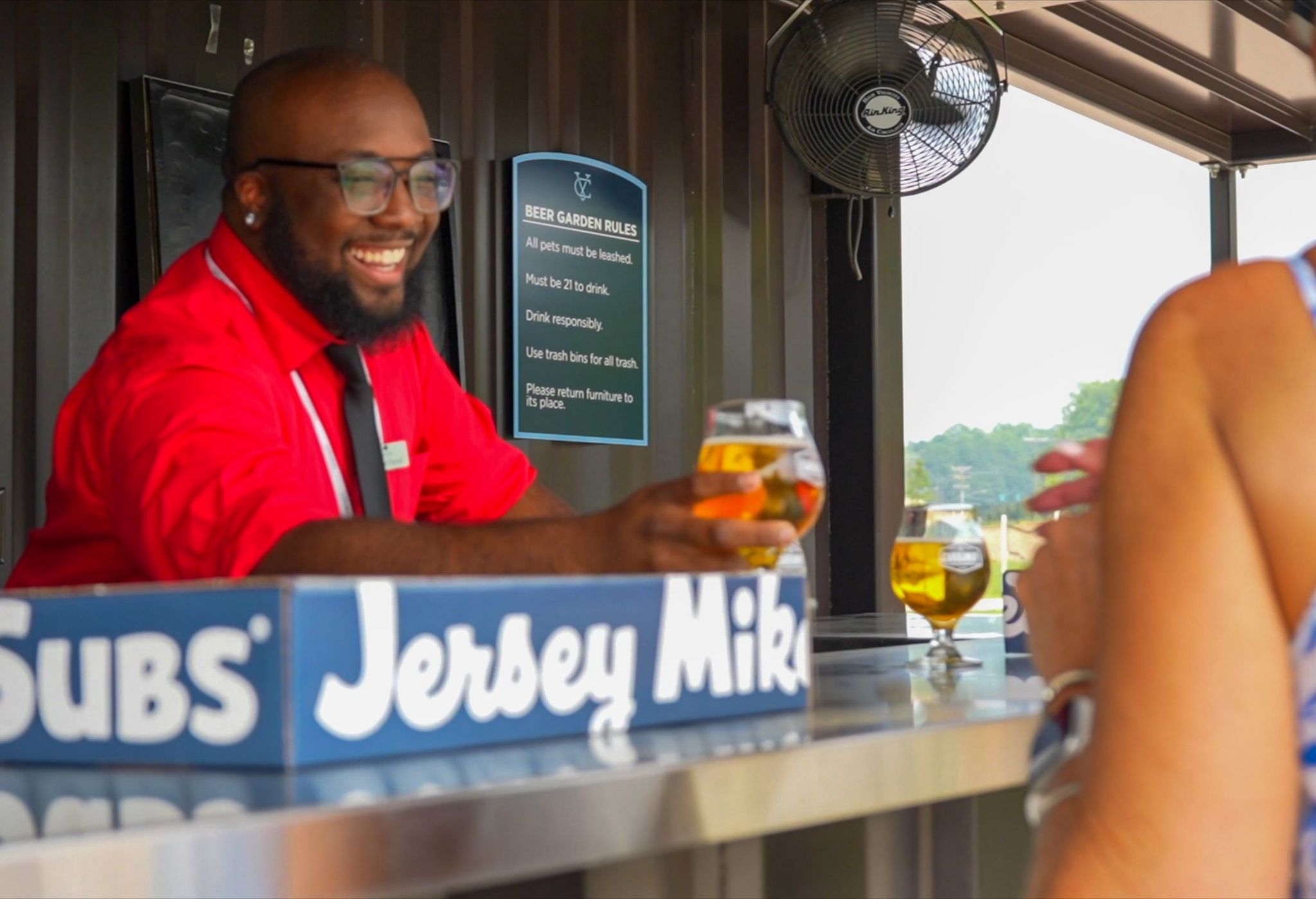 Happy friends clinking and toasting beer at beer garden patio