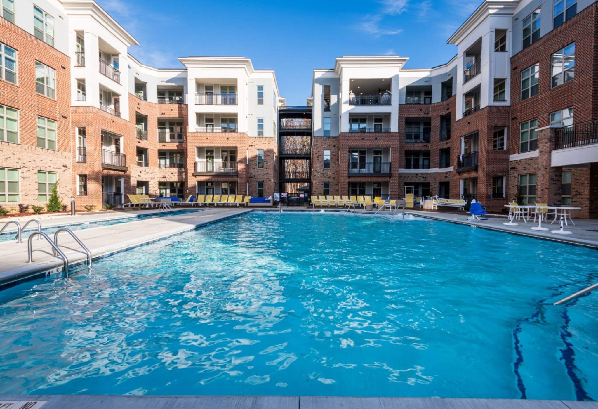Large resort-inspired pool with beautiful blue water and surrounding lounge seating