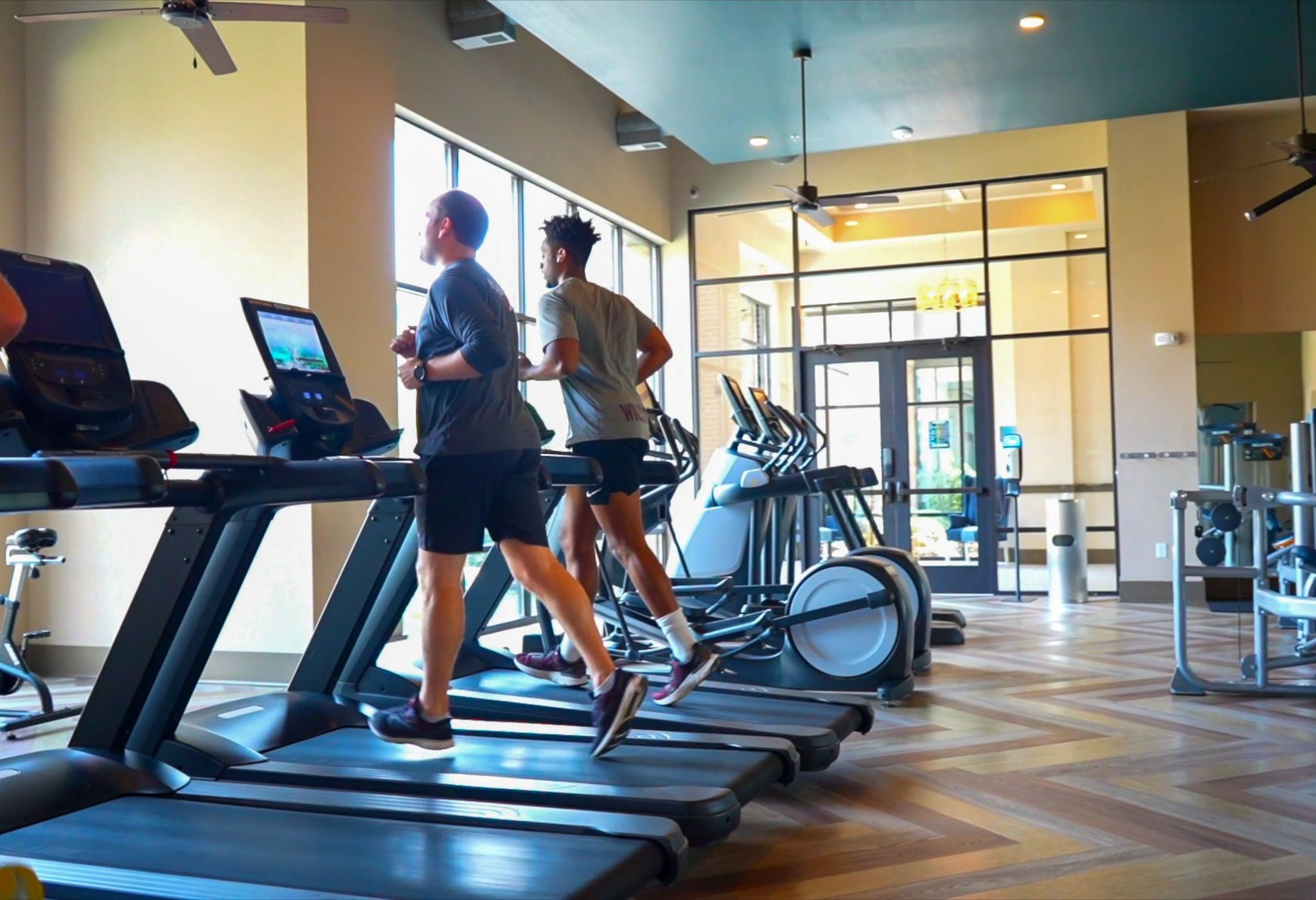 Cardio equipment including ellipticals, stair steppers, and treadmills inside large apartment fitness center